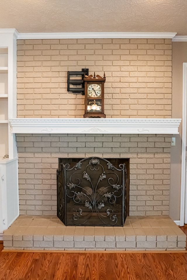 details with ornamental molding, a brick fireplace, a textured ceiling, and built in shelves