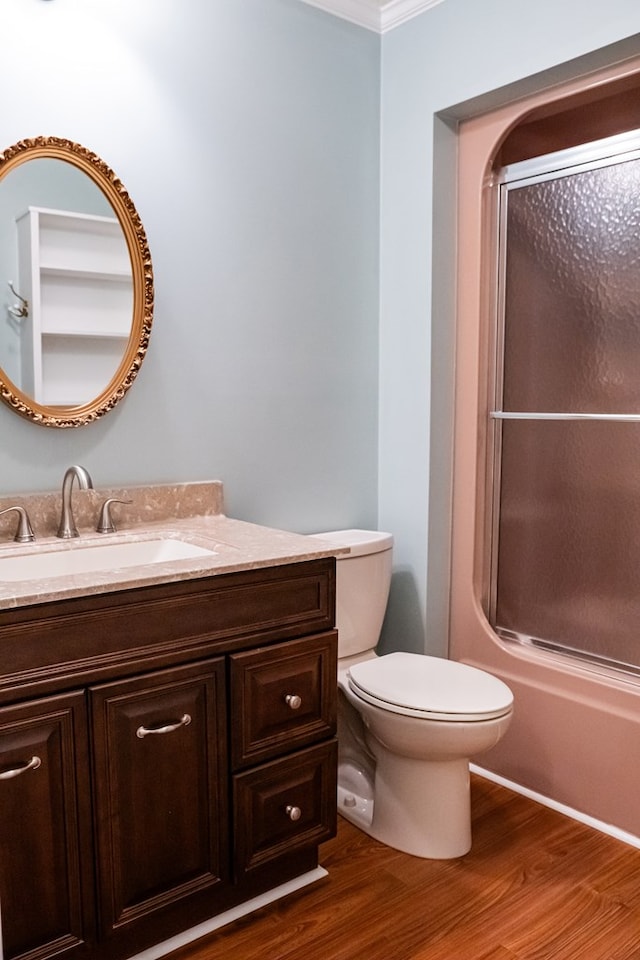 bathroom with toilet, shower / bath combination with glass door, wood finished floors, and vanity