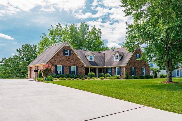 cape cod-style house featuring a garage, concrete driveway, brick siding, and a front lawn