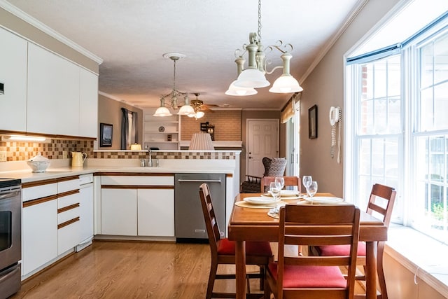 kitchen with appliances with stainless steel finishes, pendant lighting, light countertops, and white cabinetry