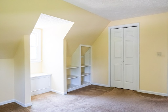 additional living space featuring light carpet, a textured ceiling, and baseboards