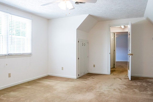 bonus room with light carpet, ceiling fan, visible vents, and a textured ceiling