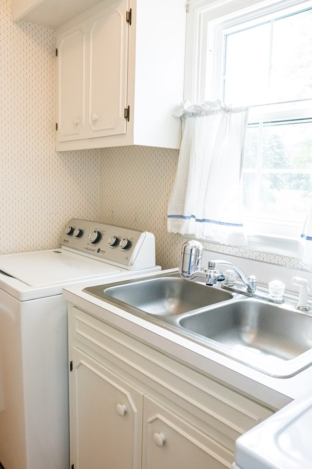 laundry room featuring independent washer and dryer, cabinet space, a sink, and wallpapered walls