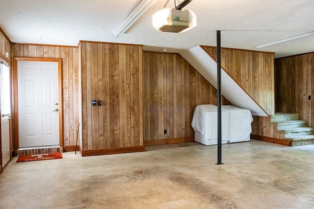 additional living space with concrete floors, wood walls, and a textured ceiling