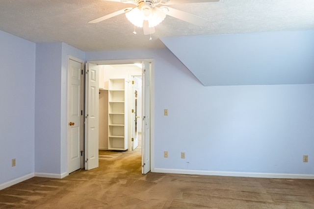 additional living space with baseboards, a ceiling fan, lofted ceiling, carpet, and a textured ceiling