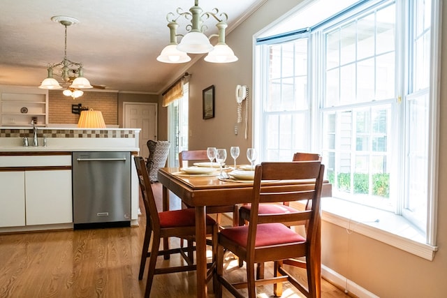 dining room with ornamental molding, wood finished floors, and an inviting chandelier