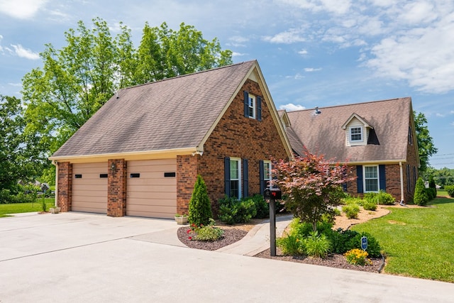 cape cod home featuring a garage, a front yard, and brick siding