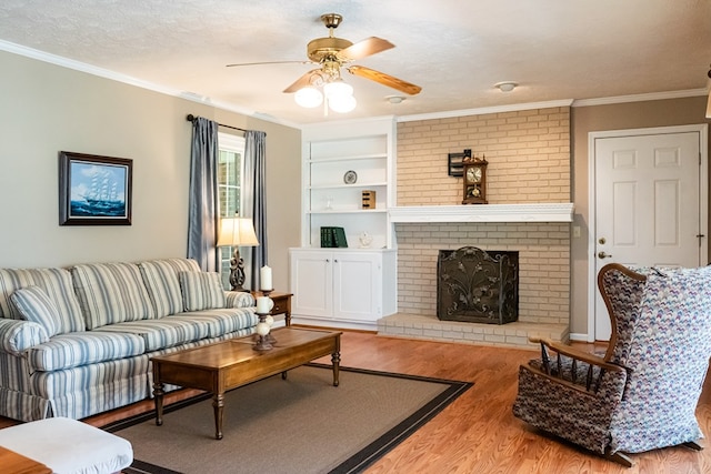 living room with ornamental molding, light wood-type flooring, a fireplace, and a textured ceiling