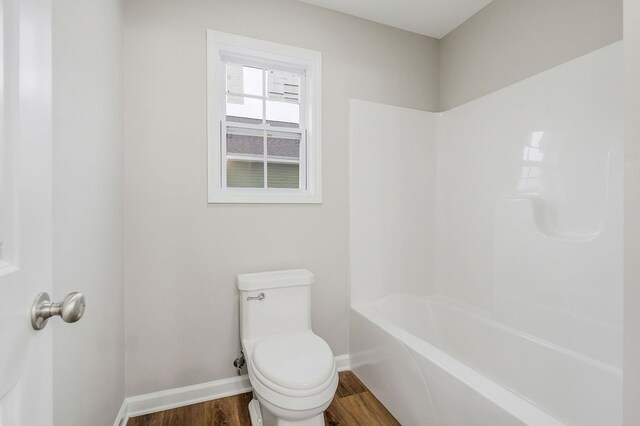 bathroom featuring toilet, baseboards, wood finished floors, and shower / bathtub combination