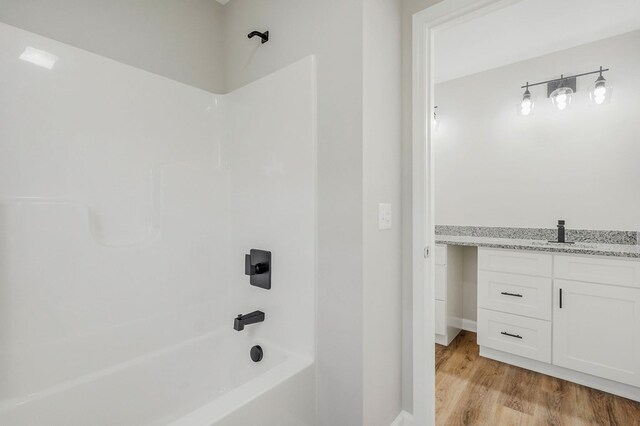 full bath featuring vanity, shower / tub combination, and wood finished floors