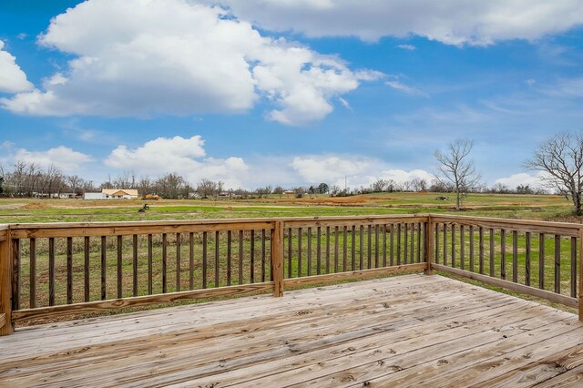 wooden deck with a rural view and a yard