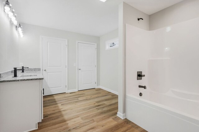 full bath featuring baseboards, vanity, shower / tub combination, and wood finished floors