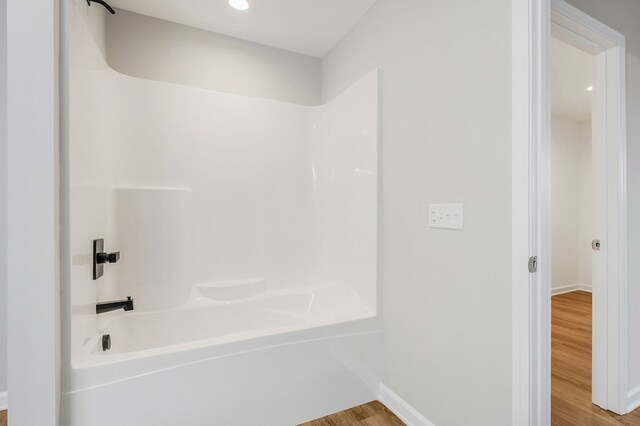 full bath featuring baseboards, wood finished floors, and shower / bathtub combination