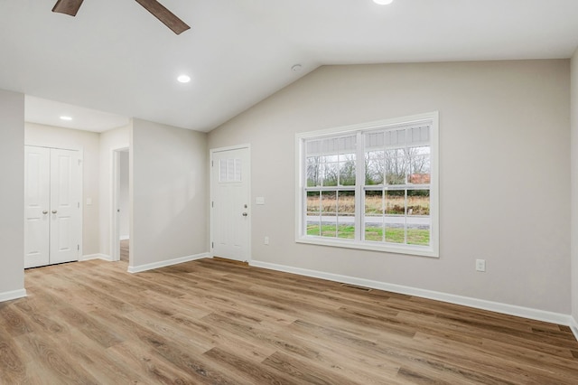 empty room featuring light wood-style floors, lofted ceiling, visible vents, and baseboards