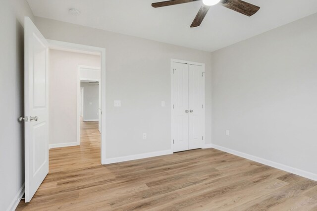 unfurnished bedroom featuring light wood finished floors, ceiling fan, baseboards, and a closet