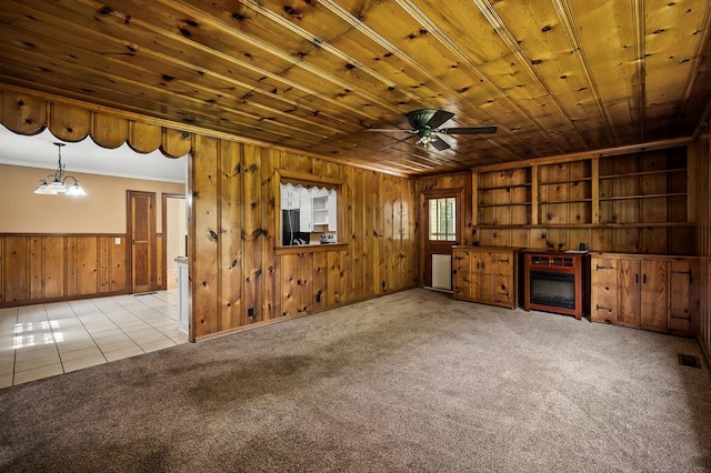 unfurnished living room featuring wood walls, light tile patterned flooring, wood ceiling, and light colored carpet