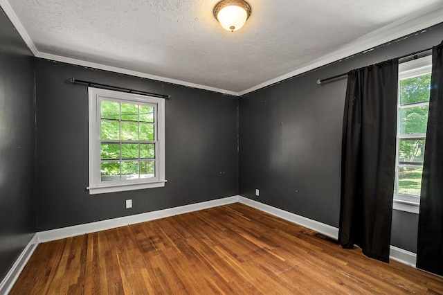 empty room with a textured ceiling, wood finished floors, and crown molding