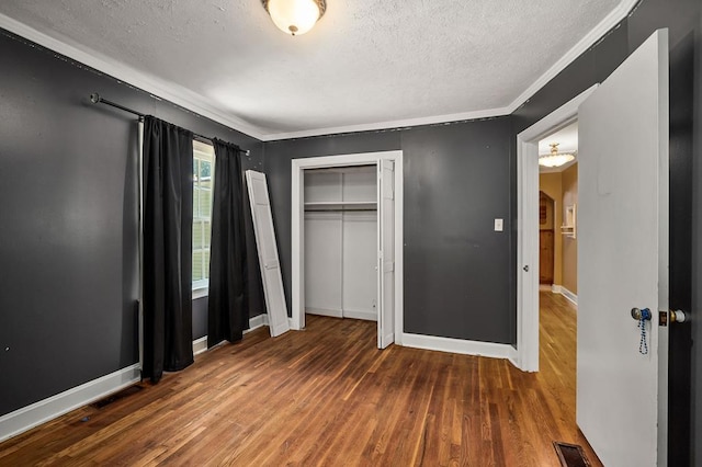 unfurnished bedroom with a textured ceiling, visible vents, baseboards, dark wood-style floors, and crown molding