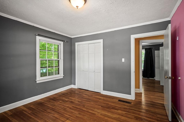 unfurnished bedroom featuring baseboards, visible vents, dark wood finished floors, crown molding, and a closet