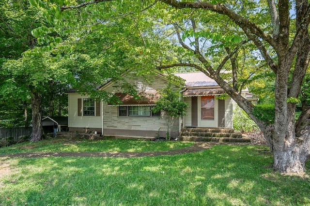 view of front facade with stone siding, a front yard, and fence