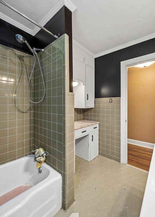 bathroom with tile walls, bathing tub / shower combination, ornamental molding, vanity, and tile patterned flooring