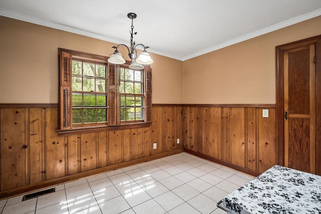 unfurnished dining area with light tile patterned floors, visible vents, a wainscoted wall, ornamental molding, and a chandelier