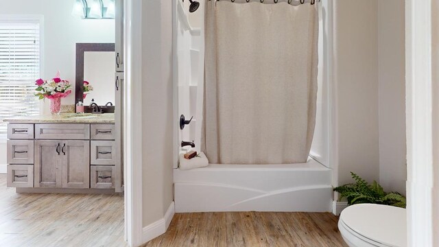 bathroom with toilet, shower / bath combo with shower curtain, wood finished floors, and vanity