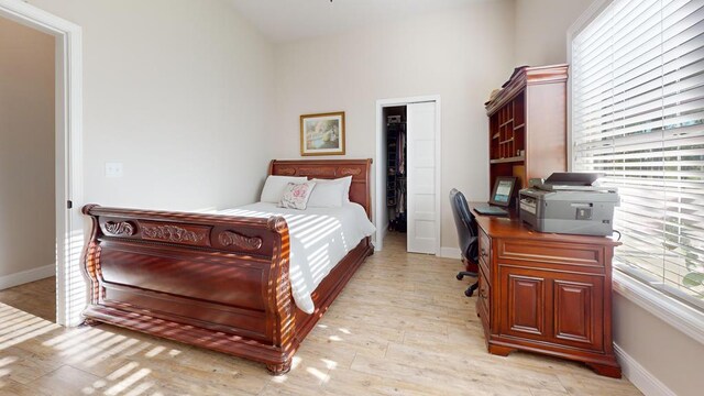 bedroom with light wood-style flooring, baseboards, and a closet