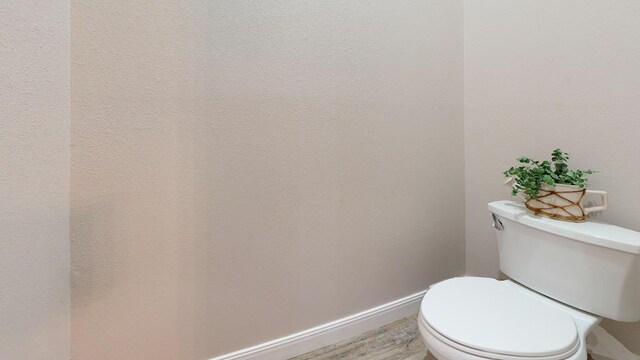 bathroom with wood finished floors, toilet, and baseboards