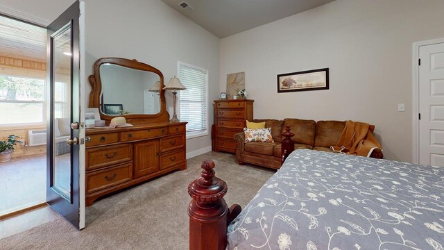 bedroom with multiple windows, a wall mounted air conditioner, visible vents, and light colored carpet