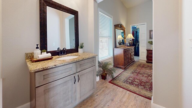 bathroom with baseboards, wood finished floors, and vanity