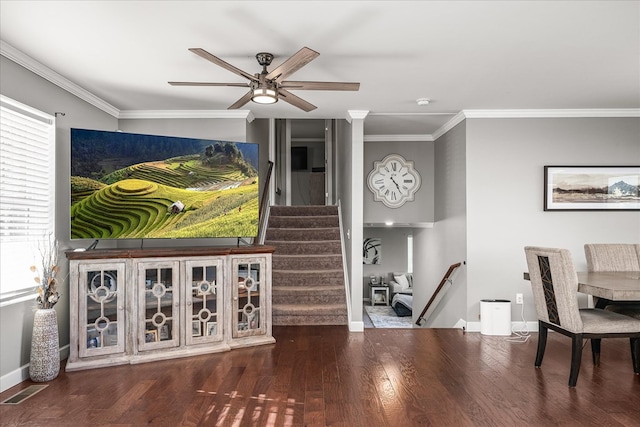 living room with crown molding, visible vents, wood finished floors, baseboards, and stairs