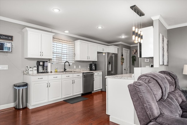 kitchen with dark wood-type flooring, a sink, white cabinetry, appliances with stainless steel finishes, and crown molding