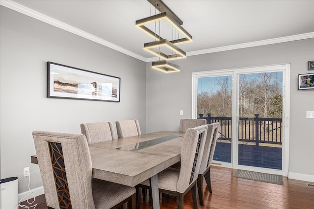 dining space featuring ornamental molding, baseboards, and wood finished floors