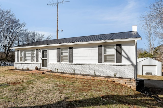 view of front of home featuring a chimney, metal roof, an outdoor structure, a front lawn, and brick siding