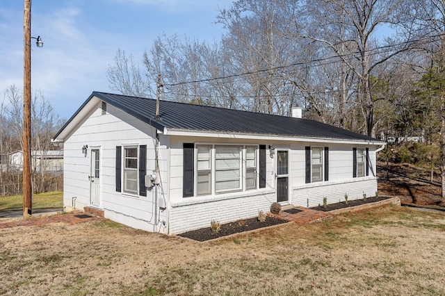 view of front of house featuring brick siding, metal roof, and a front lawn