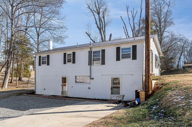 view of front of home with metal roof, a patio, and a chimney