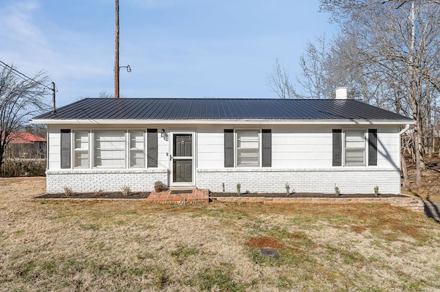 view of front of home featuring a front yard, brick siding, and metal roof