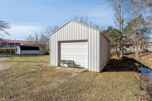 detached garage with dirt driveway and a storage shed