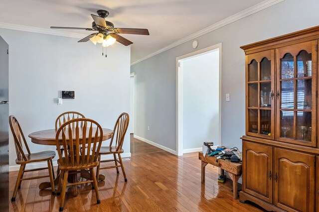 dining room featuring baseboards, ornamental molding, ceiling fan, and wood finished floors