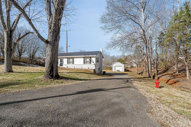 view of front facade with driveway, a garage, a front lawn, and an outbuilding