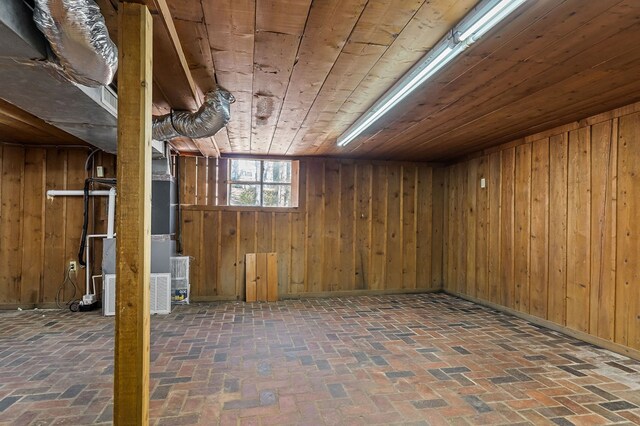 below grade area featuring wooden ceiling, wooden walls, and brick floor