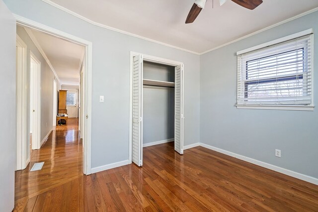 unfurnished bedroom with dark wood-type flooring, multiple windows, and crown molding