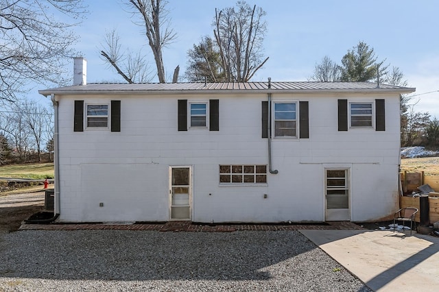 view of front of home featuring metal roof, a chimney, and a patio