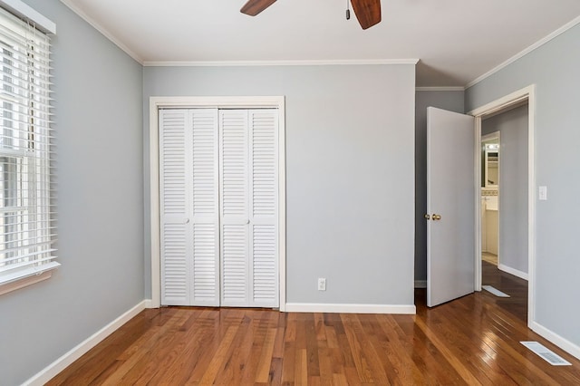 unfurnished bedroom with a closet, dark wood-style flooring, visible vents, and baseboards