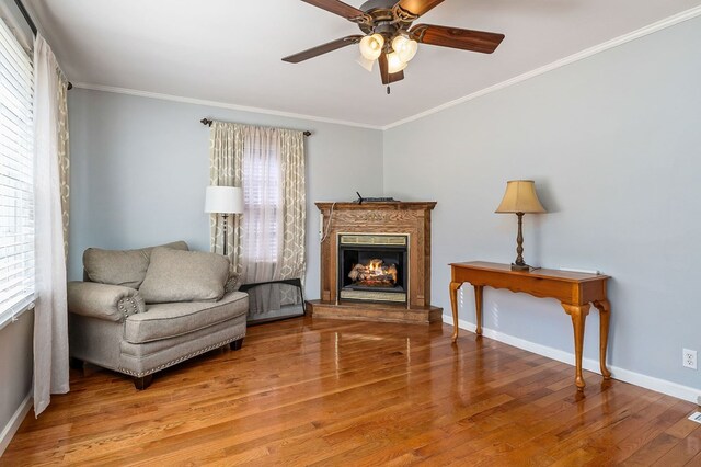 sitting room featuring baseboards, a glass covered fireplace, wood finished floors, and crown molding