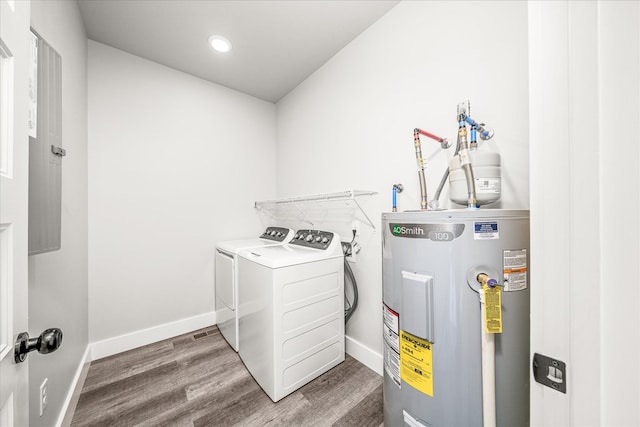 clothes washing area featuring laundry area, baseboards, dark wood-type flooring, washing machine and dryer, and water heater