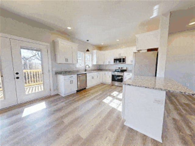 kitchen with light stone counters, light wood-style flooring, recessed lighting, stainless steel appliances, and white cabinetry