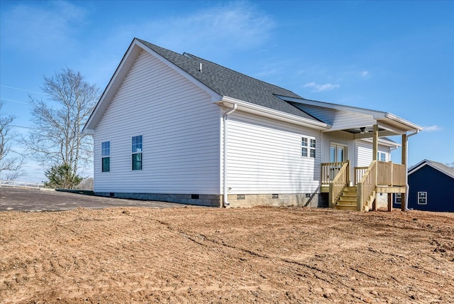 view of home's exterior with crawl space and roof with shingles