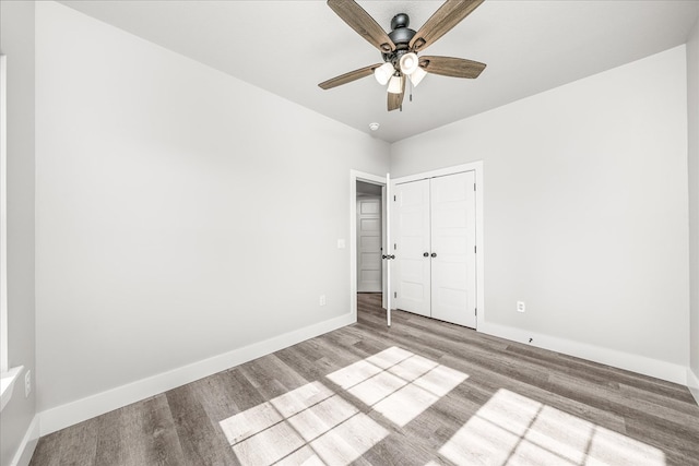 unfurnished bedroom with ceiling fan, light wood-style floors, a closet, and baseboards